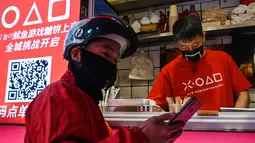 Pengantar makanan menunggu di toko kecil untuk dalgona, permen gula renyah yang muncul dalam serial Netflix Squid Game, di Shanghai pada 12 Oktober 2021. Meski Netflix tidak tersedia di China, tetapi serial Netflix Squid Game sukses meraih popularitas di Negeri Tirai Bambu itu. (Hector RETAMAL/AFP)