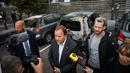 PM Swedia Stefan Lofven memberikan keterangan dengan latar belakang mobil yang hangus dan rusak di kota Gothenburg, Selasa (14/8). Menurut laporan, kelompok gangster menyiram bensin ke atap mobil lalu membakarnya. (Henrik BRUNNSGARD/TT News Agency/AFP)