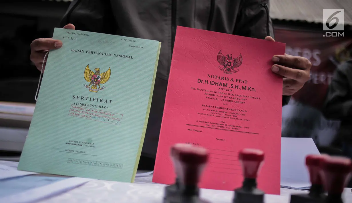 Polisi menunjukkan barang bukti sertifikat saat rilis pengungkapan sindikat kejahatan properti di Jakarta, Senin (5/8/2019). Subdit 2 Harda Dit Reskrimum PMJ mengamankan 5 tersangka dengan barang bukti seperti sertifikat palsu korban dan satu buah laptop. (Liputan6.com/Faizal Fanani)