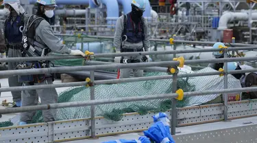 Para pekerja menyingkirkan bahan bangunan sebelum istirahat makan siang di pembangkit listrik tenaga nuklir Fukushima Daiichi, di kota Futaba, timur laut Jepang, Jumat, 14 Juli 2023. (AP Photo/Hiro Komae)