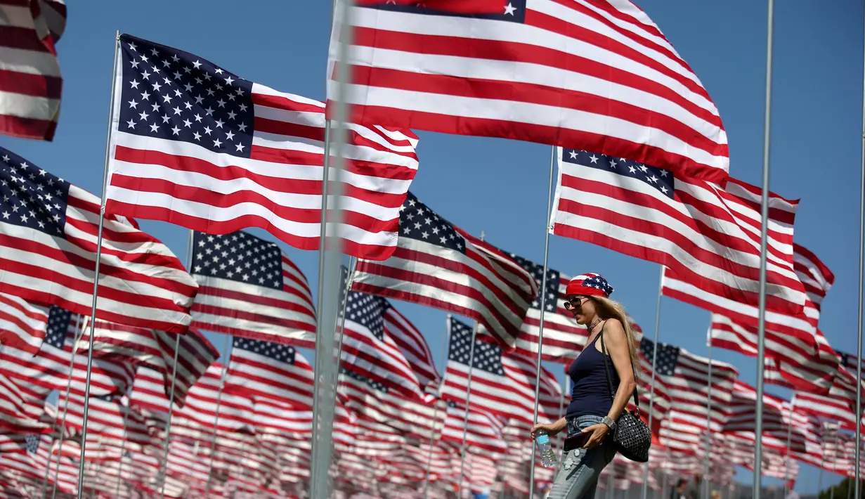 Seorang wanita berjalan diantara 3.000 bendera AS pada peringatan 15 tahun bagi para korban 11 September 2001 di Malibu, California, (11/09). Pengibaran bendera AS dilakukan sejak matahari terbit sampai terbenam. (REUTERS/Lucy Nicholso)