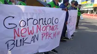 Menolak penerapan PPKM, sejumlah Pengemudi Ojek Online (Ojol) menggelar aksi damai di Bundaran Hulondalo Indah (HI), Kota Gorontalo. (Arfandi Ibrahim/Liputan6.com)