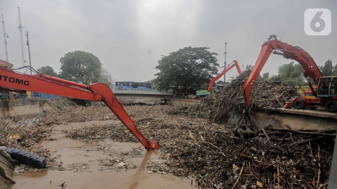 Petugas dibantu alat berat membersihkan sampah kayu dan bambu yang tersangkut di Pintu Air Manggarai, Jakarta, Rabu (9/10/2019). Sampah tersebut merupakan kiriman dari Bogor usai diguyur hujan deras tadi malam. (Liputan6.com/Faizal Fanani)