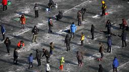 Sejumlah warga berusaha mendapatkan ikan air tawar melalui lubang kecil selama acara Festival Es di sungai yang beku di Hwacheon, selatan dari zona demiliterisasi (DMZ) yang memisahkan dua Korea, (9/1/2016). (REUTERS/Kim Hong-Ji)