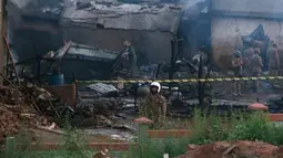 Pejabat militer Pakistan memeriksa lokasi kecelakaan pesawat di Rawalpindi, Pakistan, Selasa (30/7/2019). Kecelakaan menyebabkan 12 orang tewas dan memicu kebakaran besar yang melanda beberapa rumah. (AP Photo/Anjum Naveed)