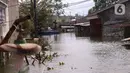 Warga melintas dengan perahu buatan saat banjir melanda perumahan Periuk Damai, Tangerang, Banten, Selasa (22/2/2021). Banjir setinggi 2,5 meter tersebut sudah terjadi selama 4 hari. (Liputan6.com/Angga Yuniar)