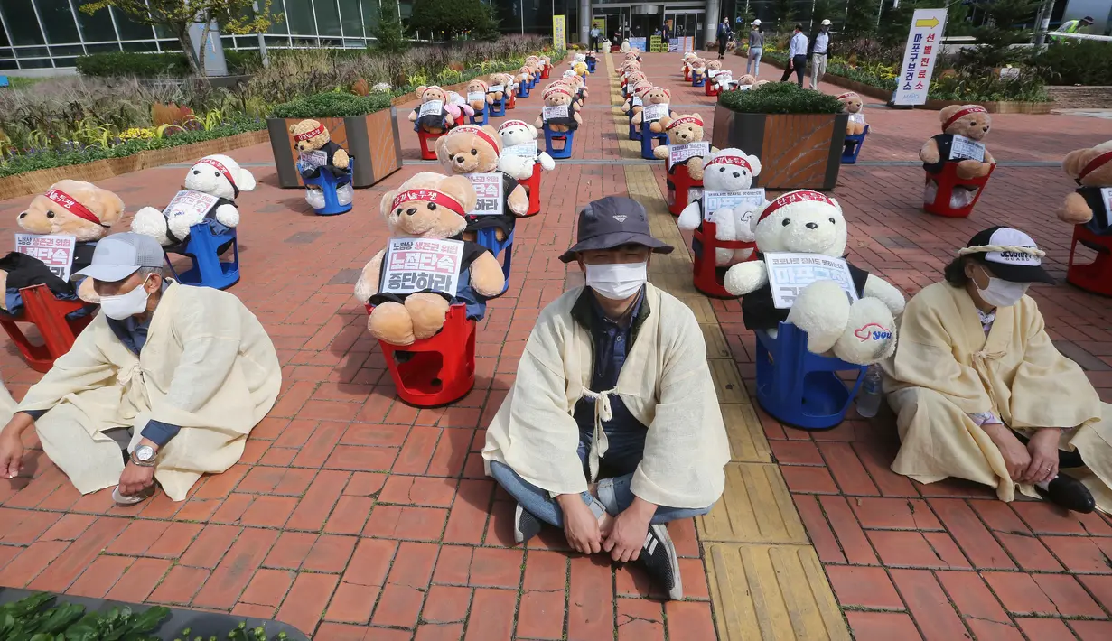 Pedagang kaki lima duduk memprotes tindakan keras terhadap PKL ilegal, di depan kantor distrik Mapo di Seoul, Kamis (24/9/2020). Mereka mengganti pengunjuk rasa dengan boneka beruang untuk menghindari pelanggaran larangan aksi dengan lebih dari 10 orang. (AP Photo/Ahn Young-joon)