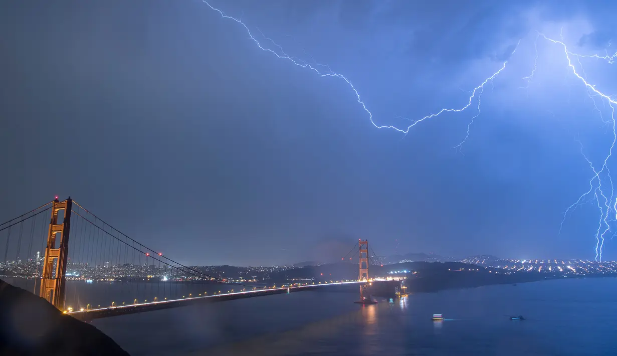 Kilatan petir hiasi jembatan Golden Gate di San Francisco, California, AS (11/9). Petir mengeluarkan suara yang menggelegar yang disebut guruh. (AFP Photo/Josh Edelson)
