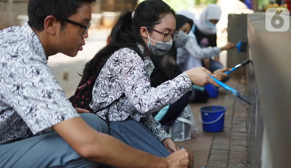 Pelajar membersihkan coretan yang mengotori tembok saat kericuhan dalam unjuk rasa di Senayan, Jakarta, Jumat (4/10/2019). Para siswa dan alumni SMA menutup coret-coretan  itu sekaligus mengampanyekan cinta damai dalam praktik demokrasi di Indonesia. (Liputan6.com/Immanuel Antonius)