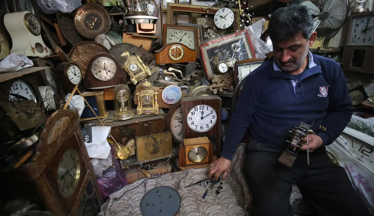 Hussein Mahmud (45) asal Irak saat memperbaiki jam kuno di gudangnya di daerah Maidan Baghdad (20/2). Mahmud mengumpulkan jam kuno berumur 60 sampai 150  tahun lalu dari pelelangan dan penjual jalanan. (AFP Photo/Ahmad Al-Rubaye)