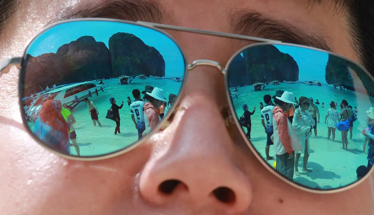 Refleksi wisatawan yang menikmati Maya Bay terlihat dari sebuah kacamata di pulau Phi Phi Leh, Thailand, Kamis (31/5). Salah satu destinasi wisata tempat syuting film The Beach ini  akan ditutup selama empat bulan mulai 1 Juni. (AP Photo/Sakchai Lalit)