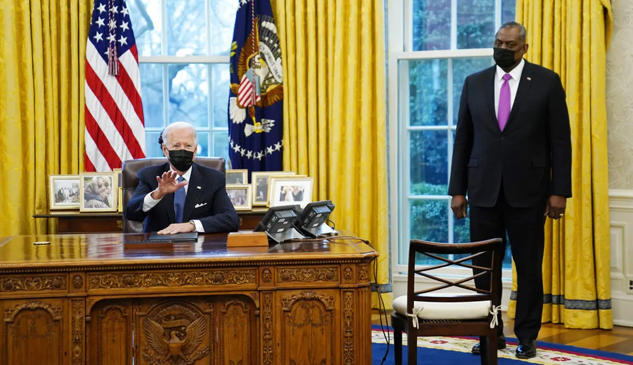 Menteri Pertahanan Lloyd Austin mendengarkan Presiden AS Joe Biden berbicara sebelum menandatangani Perintah Eksekutif yang membatalkan larangan bagi transgender untuk masuk militer AS pada era Donald Trump di Kantor Oval Gedung Putih, Washington, Senin (25/1/2021). (AP Photo/Evan Vucci)