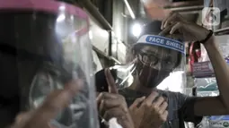 Pembeli mencoba alat pelindung wajah atau face shield di salah satu kios Pasar Pramuka, Jakarta, Rabu (3/6/2020). Pemerintah mewajibkan petugas pelayanan, pedagang, serta pekerja toko swalayan dan mal mengenakan face shield saat fase new normal diterapkan. (merdeka.com/Iqbal S. Nugroho)