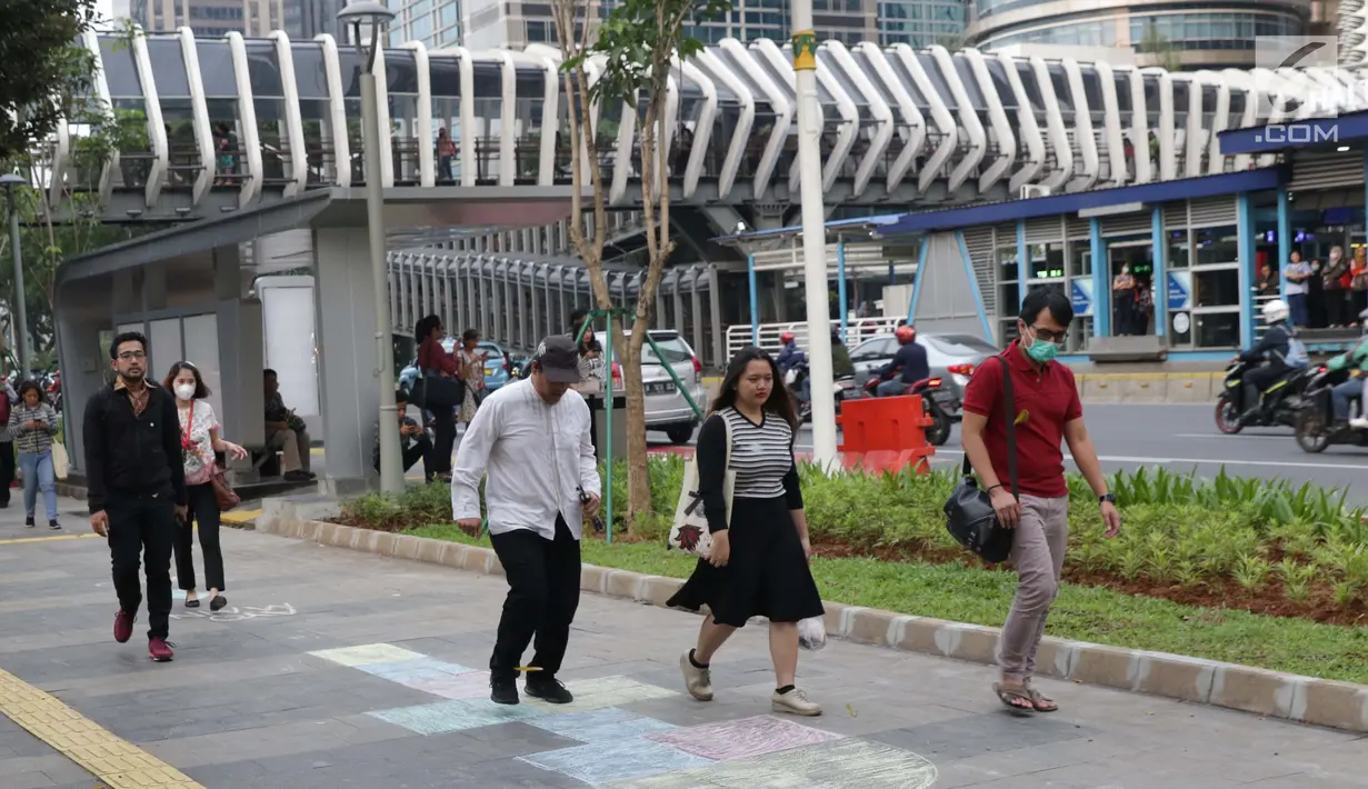 Warga mencoba permainan anak engkle di trotoar sekitar Halte Gelora Bung Karno, Jakarta, Jumat (17/5/2019). Koalisi Pejalan Kaki melakukan eksperimen permainan untuk mengedukasi kegiatan mengembalikan fungsi trotoar lebih dari sekedar ruang berjalan kaki. (Liputan6.com/Helmi Fithriansyah)