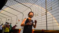 Pelangi terlihat melalui pagar saat seorang wanita berjalan di Central Television Tower di Beijing (26/8/2021). Keindahan pelangi ganda dimanfaatkan warga Beijing untuk diabadikan lewat foto dan berfoto dengan latar pelangi itu. (AFP/Jade Gao)