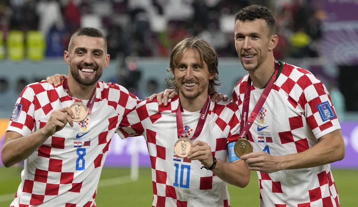 Tiga pemain Kroasia, Luka Modric (tengah), Mateo Kovacic (kiri), dan Ivan Perisic berpose dengan medali setelah meraih peringkat ketiga di Piala Dunia 2022. Ini merupakan kedua kalinya Kroasia meraih peringkat ketiga dalam perhelatan akbar empat tahunan ini, sebelumnya pada Piala Dunia 1998 Kroasia langsung menjadi tim peringkat ketiga dalam debut mereka di Piala Dunia. (AP Photo/Frank Augstein)