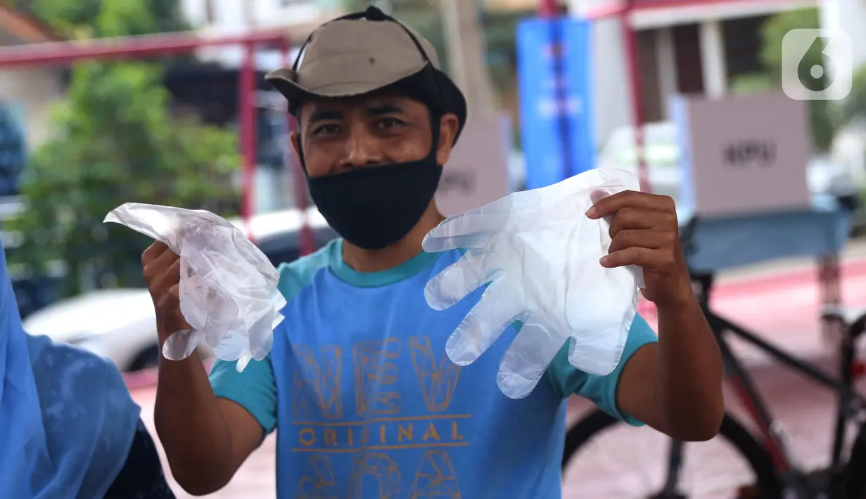 Pemiilih mengenakan sarung tangan plastik saat menggunakan hak suaranya dalam Pilkada Tangerang Selatan di TPS 23 Pondok Jagung Timur, Rabu (9/12/2020). Menggunakan masker hingga memakai sarung tangan plastik menjadi hal wajib saat melakukan pencoblosan di Pilkada 2020. (Liputan6.com/Angga Yuniar)