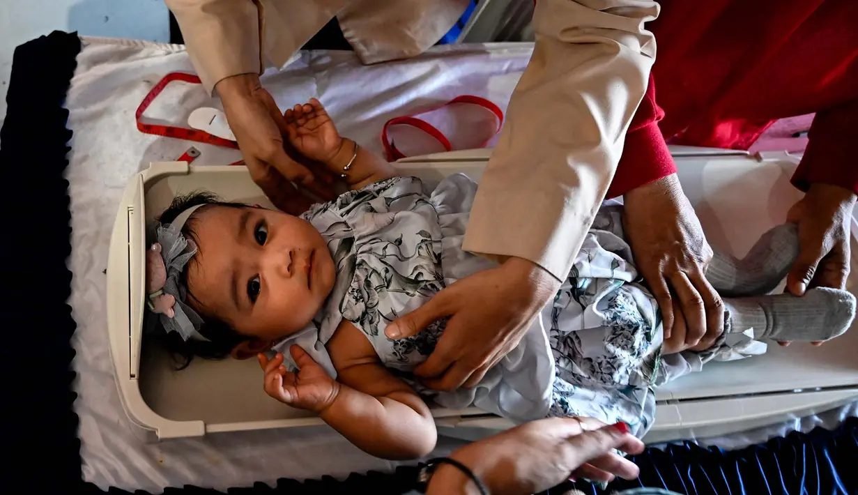 Seorang petugas kesehatan menimbang berat bayi dalam program pemeriksaan kesehatan bulanan untuk anak-anak di sebuah pusat layanan terpadu di Banda Aceh, Senin,  10 Agustus 2026. (AFP/ Chaideer Mahyuddin)