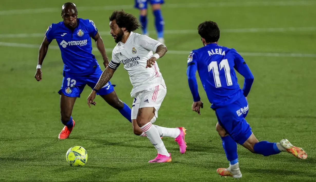 Pemain Real Madrid Marcelo (tengah) menggiring bola melewati pemain Getafe Alena (kanan) dan Allan Nyom (kiri) pada pertandingan Liga Spanyol di Stadion Alfonso Perez, Getafe, Spanyol, Minggu (18/42021). Pertandingan berakhir dengan skor 0-0. (AP Photo/Manu Fernandez)