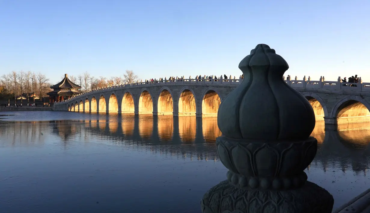 Foto yang diabadikan pada 4 Desember 2020 ini menunjukkan matahari terbenam yang menyinari Jembatan 17 Lengkung di Istana Musim Panas di Beijing, ibu kota China. (Xinhua/Chen Jianli)