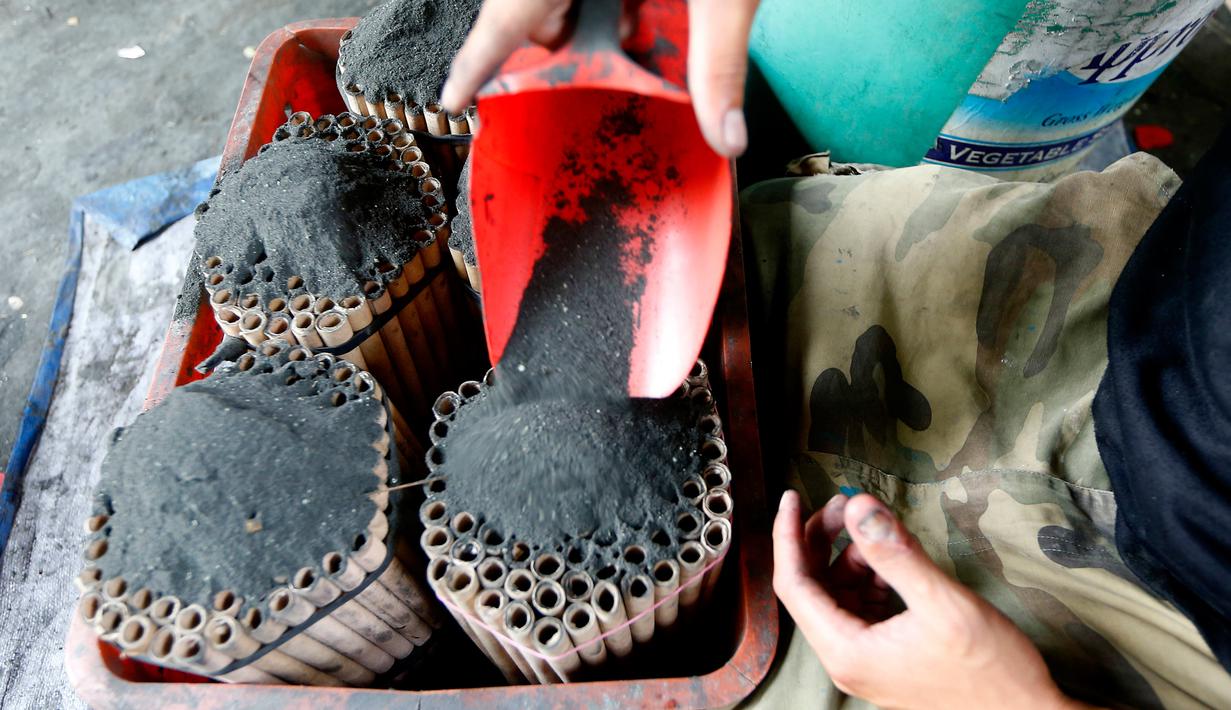 Pekerja memasukkan bubuk mesiu ke dalam sebuah tabung kecil saat membuat kembang api di sebuah gubuk, provinsi Bulacan, utara Manila, Rabu (27/12). Warga Filipina menyiapkan kembang api untuk menyambut tahun baru 2018. (AP/Bullit Marquez)