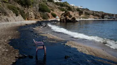 Kursi plastik di pinggir pantai yang berwarna hitam di Pulau Salamina, Yunani, Selasa (12/9). Warna hitam itu berasal dari tumpahan minyak kapal tanker Agia Zoni II yang tenggelam Minggu lalu saat akan berlabuh di pantai Salamina. (AP/Petros Giannakouris)