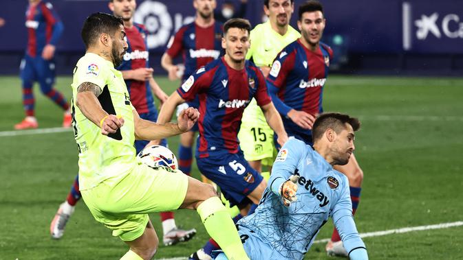 Striker Atletico Madrid, Luis Suarez, saat melepaskan tembakan di depan kiper Levante, Aitor Fernandez, dalam laga tunda jornada kedua La Liga 2020/2021 di Estadio Ciudad de Valencia, Kamis (18/2/2021) dini hari WIB. Levante dan Atletico Madrid bermain imbang 1-1. (JOSE JORDAN / AFP)