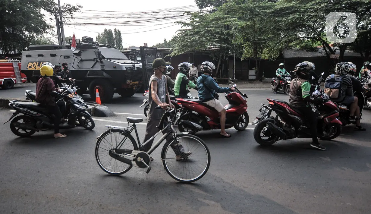 Pengendara motor dan sepeda melintas dekat kendaraan taktis TNI dan Polri saat penyekatan PPKM Darurat di kawasan Lampiri, Kalimalang, Jakarta, Senin (5/7/2021). Penyekatan ini dilakukan untuk membatasi pergerakan di perbatasan Jakarta guna memutus penyebaran COVID-19. (merdeka.com/Iqbal S. Nugroho)