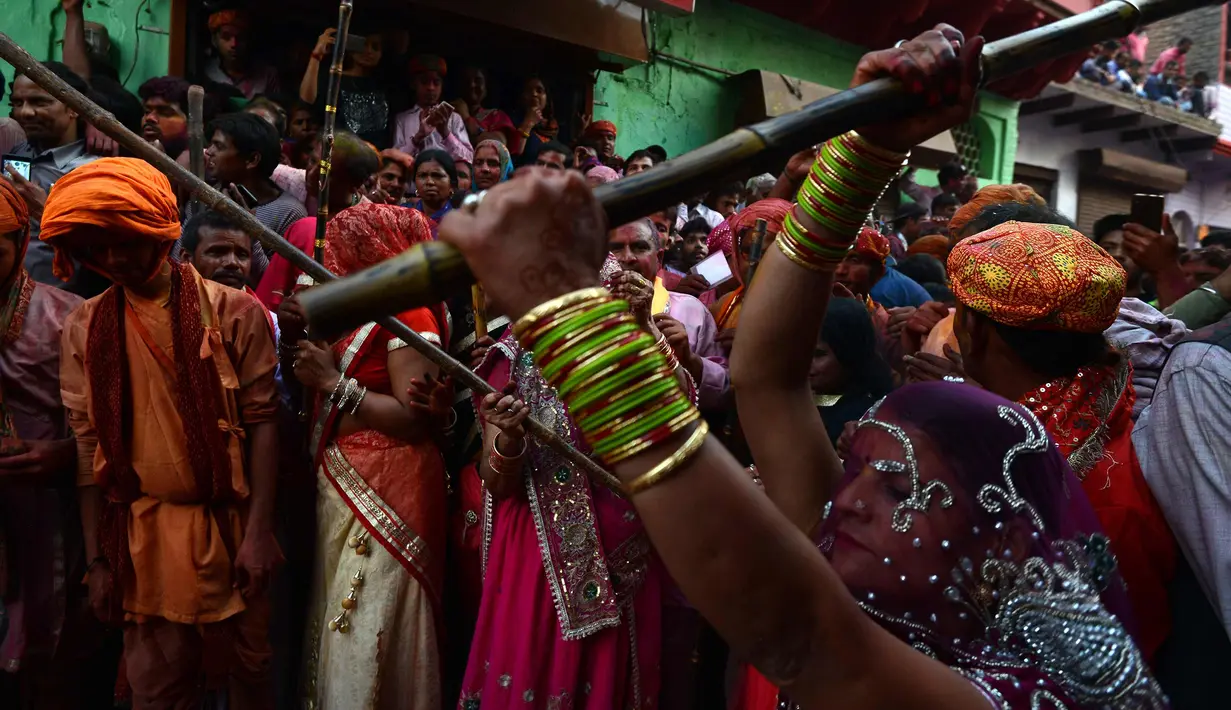 Sejumlah wanita memukul pria dengan tongkat (lathi) selama perayaan Lathmar Holi di Barsana di Mathura, India, (24/2). Lathmar Holi adalah perayaan lokal festival Hindu Holi, biasanya beberapa hari sebelum festival Holi. (AFP Photo/Dominique Faget)