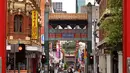 Orang-orang berjalan di jalan yang sepi di Chinatown Melbourne, Australia, Selasa (19/10/2021). Melbourne bersiap mencabut aturan penguncian pekan ini setelah kota tersebut berada dalam enam pekan lockdown selama 262 hari atau hampir sembilan bulan sejak Maret 2020. (William WEST/AFP)