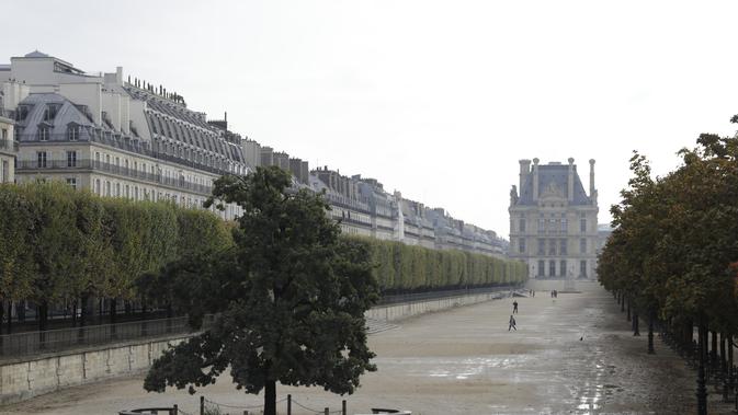 Orang-orang berjalan di taman Tuileries yang kosong di Paris (14/10/2020). Laporan media Prancis mengatakan Macron juga akan meningkatkan upaya di media sosial untuk mendesak perlunya perlindungan virus di kalangan anak muda. (AP Photo/Lewis Joly)