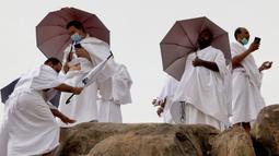 Jemaah haji menaiki Jabal al-Rahma (Gunung Rahmat) saat menunaikan prosesi wukuf di Padang Arafah, tenggara Kota Suci Mekah, Arab Saudi, Senin (19/7/2021). Ibadah haji tahun ini hanya diikuti oleh 60 ribu orang jemaah saja. (FAYEZ NURELDINE/AFP)