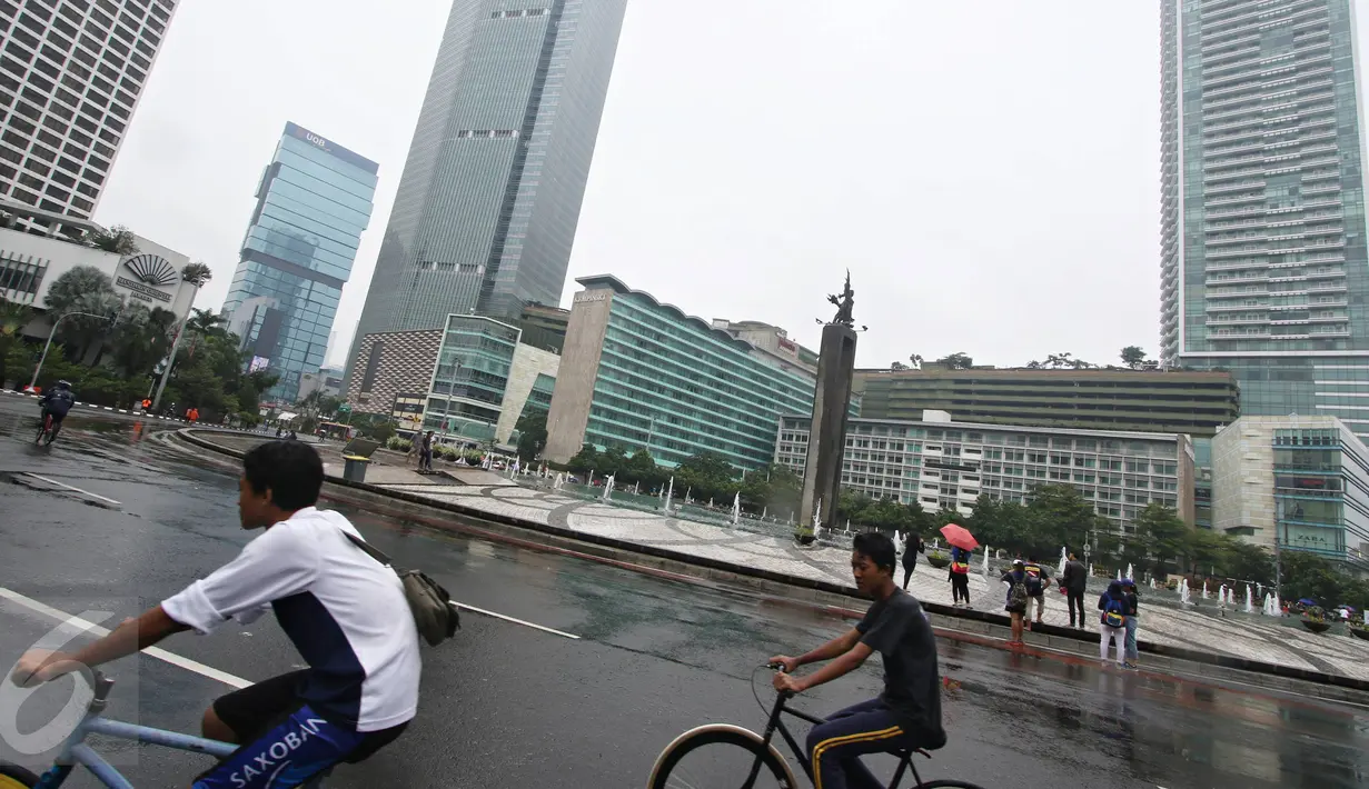 Dua warga bersepeda di kawasan Car Free Day, Jakarta, Minggu (28/2/2016). Hujan yang mengguyur Ibukota sejak semalam hingga pagi membuat kawasan CFD sepi pengunjung. (Liputan6.com/Immanuel Antonius)