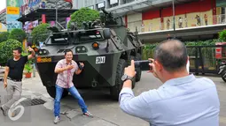 Sejumlah warga melakukan selfie dengan latar belakang Panser Anoa milik TNI di LTC Glodok, Jakarta, Jumat (4/11). Pengamanan ini merupakan bentuk kerja sama antara TNI-Polri dalam menjaga keamanan terkait demo bela islam . (Liputan6.com/Angga Yuniar)