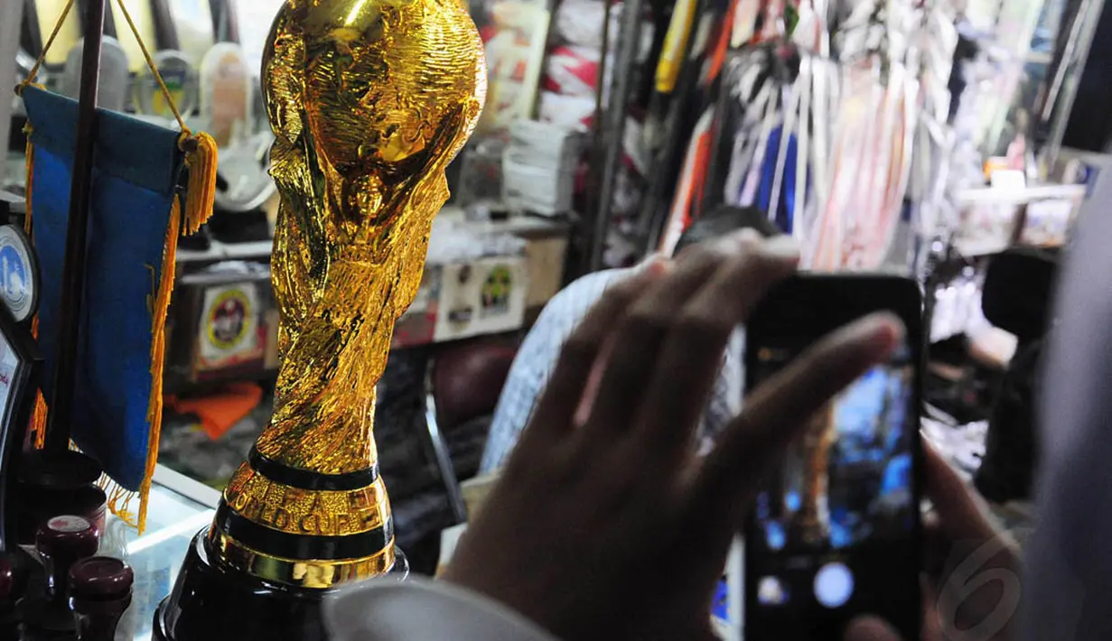 Seorang pengunjung tampak mengambil gambar replika Piala Dunia di sebuah toko kawasan Pasar Senen, Jakarta, Selasa (24/6/14). (Liputan6.com/Faizal Fanani) 