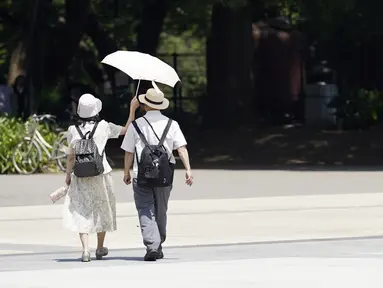 Orang-orang berbagi payung di bawah terik matahari di Taman Ueno, Selasa, di Tokyo pada 11 Juli 2023. (AP Photo/Eugene Hoshiko)