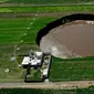 Pemandangan udara dari sinkhole yang ditemukan oleh petani di lahan pertanian di Santa Maria Zacatepec, negara bagian Puebla, Meksiko, Senin (1/6/2021). Warga tiap hari khawatir karena sinkhole terus membesar dan mengancam menelan rumah mereka. (JOSE CASTAÑARES/AFP)