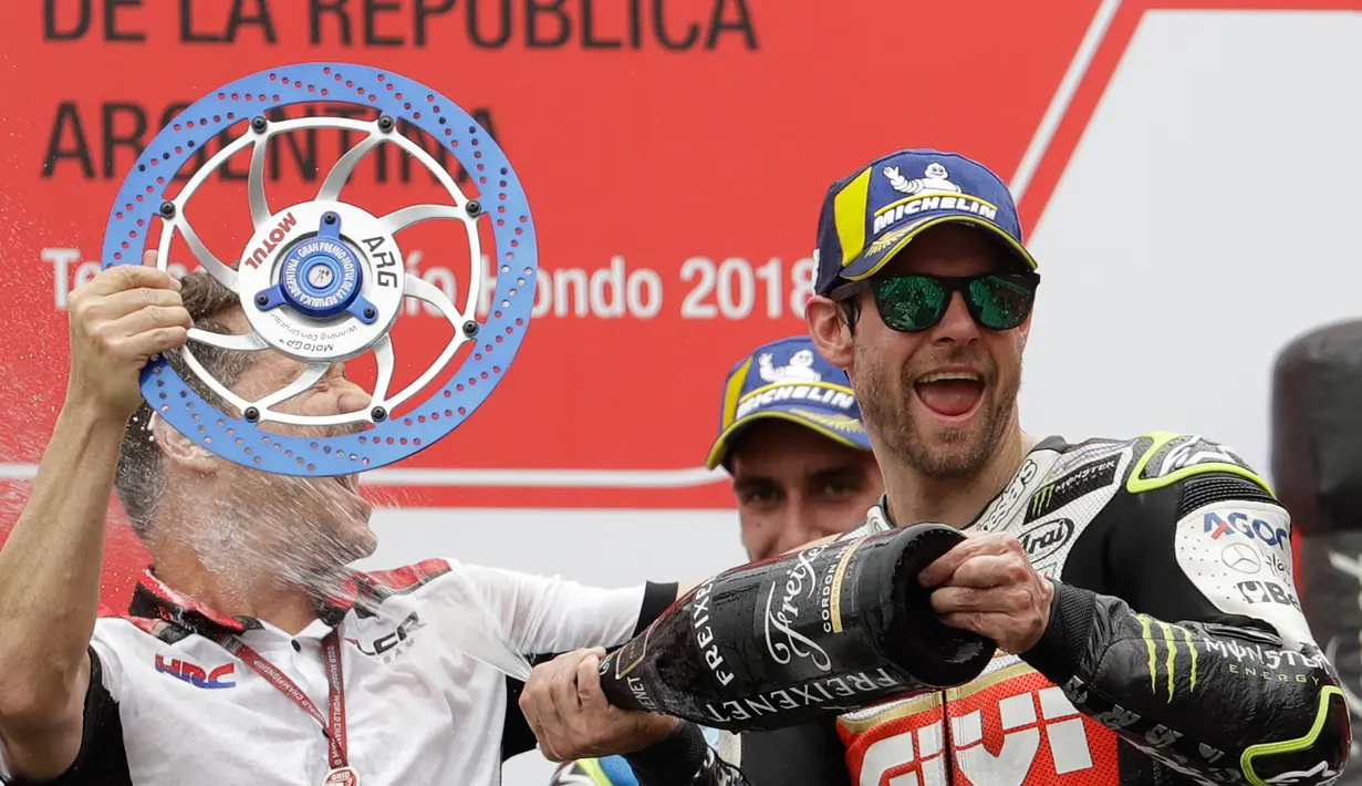 Pembalap LCR Honda, Cal Crutchlow menyemprotkan sampanye pada salah satu krunya saat merayakan kemenangannya pada balapan MotoGP Argentina di atas podium Sirkuit Termas de Rio Hondo, Minggu (8/4). (AP/Natacha Pisarenko)
