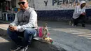 Seorang lelaki duduk dekat patung Santa Muerte saat merayakan tahun baru di Meksiko, Minggu (1/1/2017). Warga Meksiko berkeliling sambil membawa patung Santa Muerte agar memperoleh keberuntungan. (REUTERS/Carlos Jasso)
