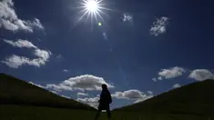 Seorang wanita berjalan di antara gundukan tanah di Northala Fields Country Park di London, Senin, 21 Agustus 2023. (AP Photo/Kirsty Wigglesworth)