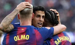 Bek Barcelona, Joao Cancelo, merayakan golnya bersama dua rekan setimnya, Dani Olmo dan Raphinha, ketika menghadapi Sevilla dalam lanjutan La Liga Spanyol di Camp Nou, Minggu (15/3/2026) malam WIB. (Lluis GENE / AFP)