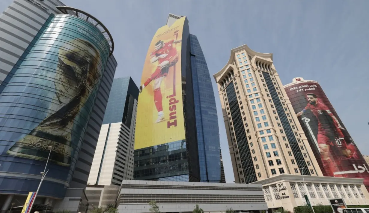 <p>Gambar besar trofi Piala Dunia (kiri), penyerang Wales Gareth Bale (tengah), dan penyerang Qatar Hassan al-Haydos (kanan) menghiasi gedung-gedung jelang Piala Dunia 2022 di Doha, Qatar, Minggu (6/11/2022). Piala Dunia 2022 akan dimulai pada 20 November 2022 hingga 18 Desember dengan menampilkan pertandingan pembuka antara tuan rumah Qatar vs Ekuador pada 20 November 2022. (Giuseppe CACACE/AFP)</p>