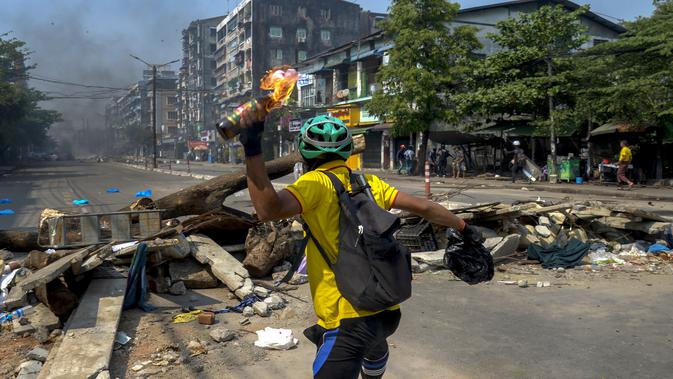 Seorang pengunjuk rasa anti-kudeta melemparkan bom molotov ke arah polisi anti huru hara saat mereka bergerak menuju tempat tinggal di Yangon, Myanmar, Rabu (17/3/2021). (AP Photo)