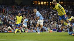 Erling Haaland kembali mencetak gol pada menit ke-23. Kali ini giliran kaki kanannya yang menjebol gawang Nottingham Forest usai mendapatkan bola liar di depan gawang Dean Henderson yang didahului oleh aksi Phil Foden. (AP/Dave Thompson)