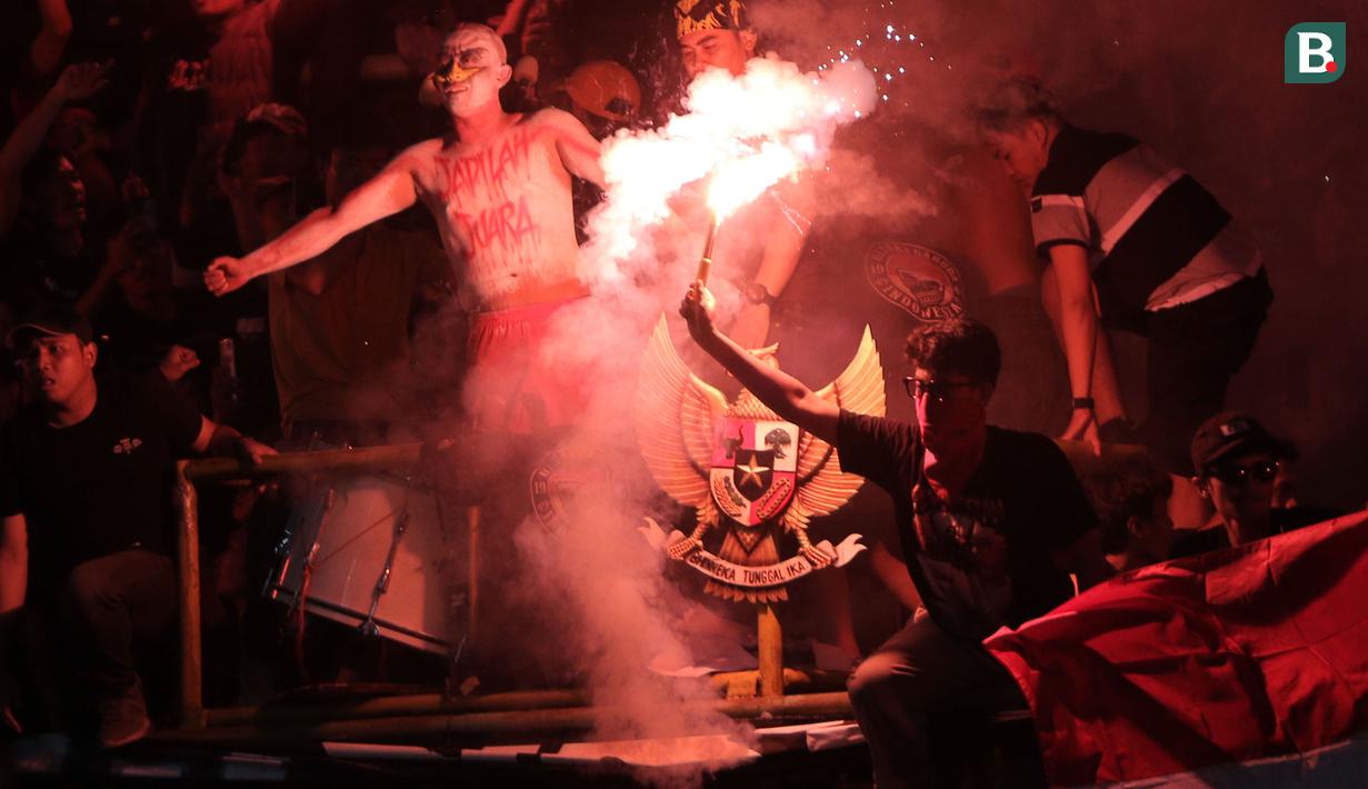 Suporter Timnas Indonesia U-19 menyalakan suar saat laga Grup A Piala AFF U-19 2022 antara Timnas Indonesia U-19 melawan Timnas Vietnam U-19 di Stadion Patriot Candrabhaga, Bekasi, Jawa Barat, Sabtu (02/07/2022). (Bola.com/Ikhwan Yanuar)
