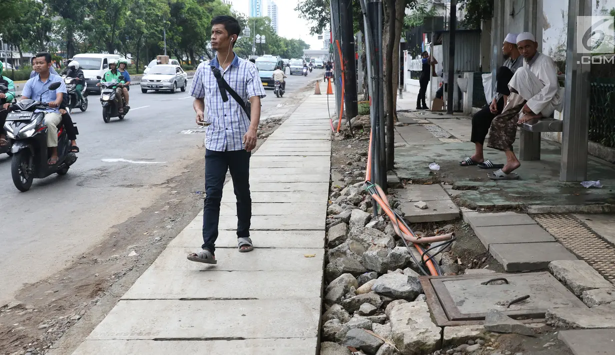 Pejalan kaki melintasi bekas galian gorong-gorong di Jalan Hayam Wuruk, Jakarta, Rabu (20/2). Tidak maksimalnya perbaikan pascapembongkaran gorong-gorong menyebabkan trotoar di kawasan itu dipenuhi kerikil serta batu. (Liputan6.com/Immanuel Antonius)