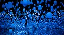 Seorang wanita berjalan di ruangan yang penuh instalasi lampu gantung di Mori Building Digital Museum Seni, Tokyo, Jepang (1/5). Tokyo menggelar pameran seni digital yang menggabungkan proyeksi gambar dan suara. (AFP Photo/Behrouz Mehri)
