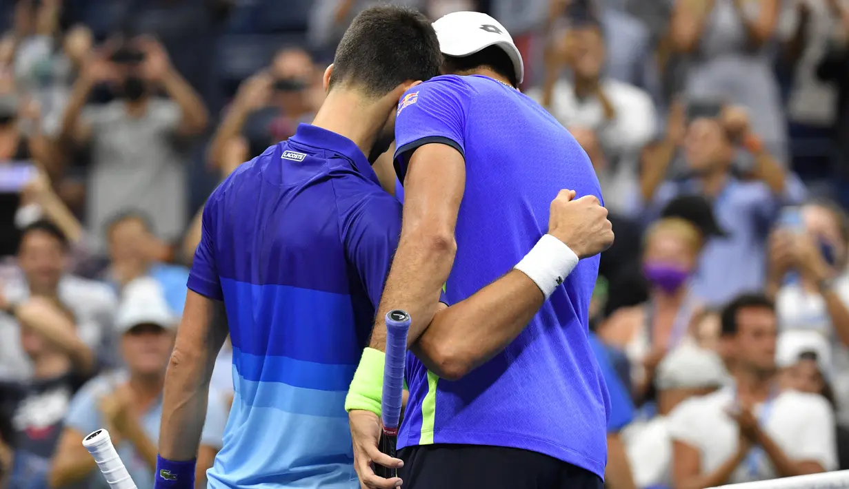Petenis Serbia, Novak Djokovic (kiri) dan Matteo Berrettini dari Italia berpelukan setelah pertandingan perempat final AS Terbuka 2021 di Arthur Ashes Stadium, New York, Kamis (9/9/2021). Petenis nomor satu dunia, Novak Djokovic melaju ke semifinal setelah menang 5-7, 6-2, 6-2, 6-3. (Ed JONES/AFP)