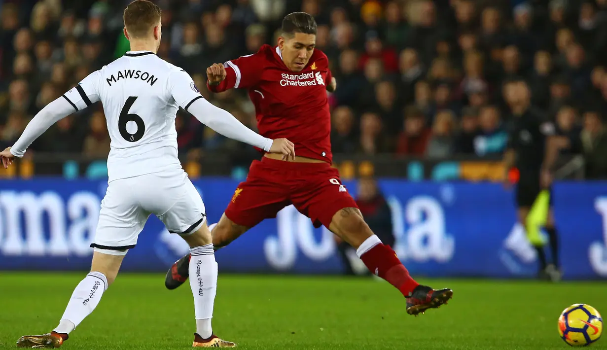 Pemain Liverpool, Roberto Firmino berebut bola dengan bek Swansea City, Alfie Mawson dalam lanjutan Premier League di Stadion Liberty, Selasa (23/1). Liverpool tumbang 0-1 dari penghuni dasar klasemen Liga Inggris Swansea. (Geoff CADDICK/AFP)
