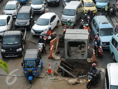 Pengendara motor menghindari lubang besar saluran air di perempatan Jalan Matraman Raya, Jakarta, Selasa (19/1/2016). Jalan Matraman Raya yang mengarah Kramat Raya macet parah imbas dari perbaikan saluran air. (Liputan6.com/Helmi Fithriansyah)